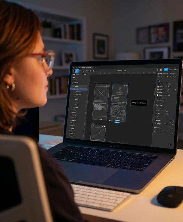 Designer exploring layouts on a laptop in warm studio light